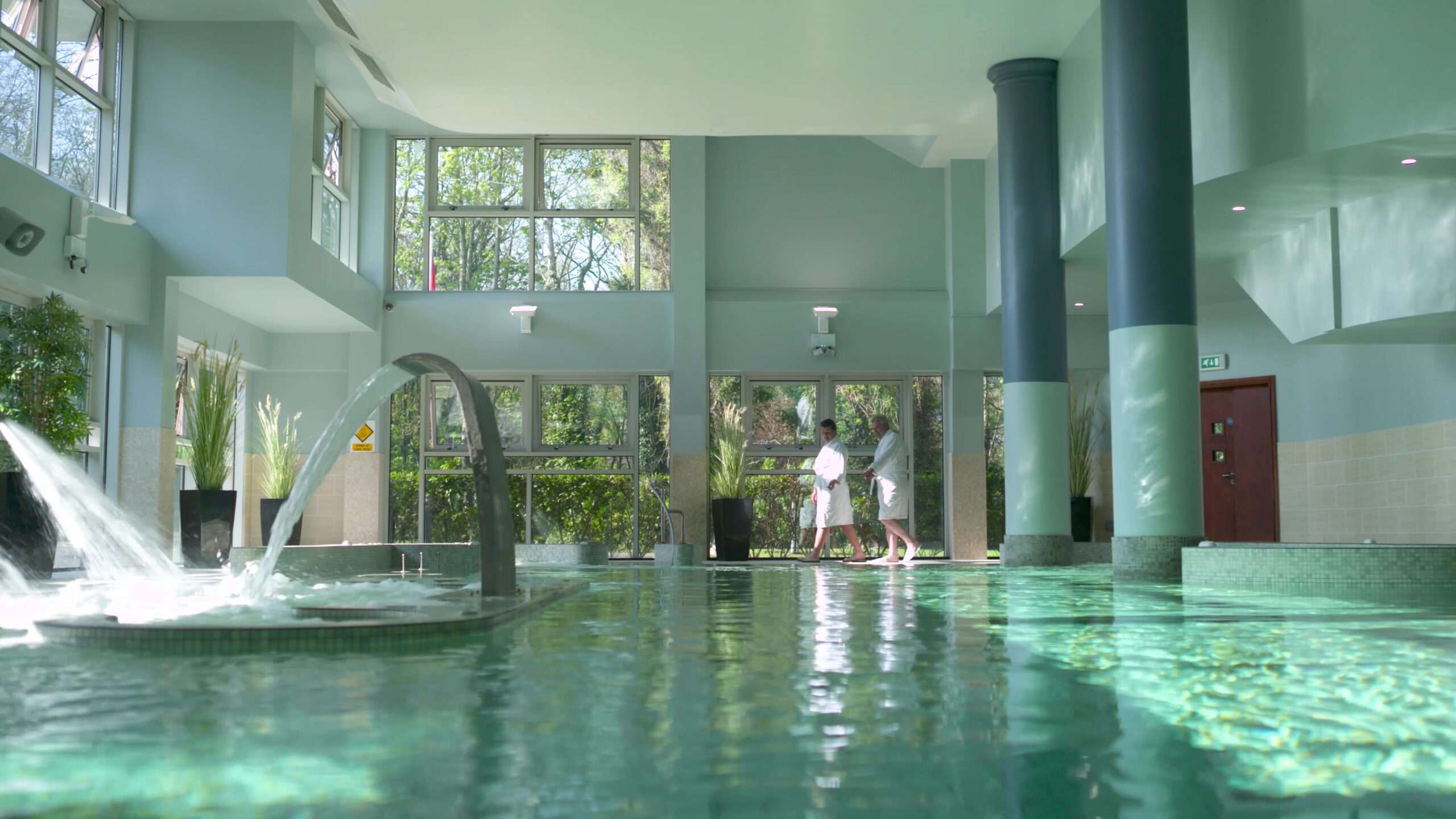 Guests walking on the side of the indoor heated pool at Radisson Blu Hotel & Spa Cork on a bright sunny day